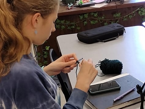 A member working on their own self project made of yarn