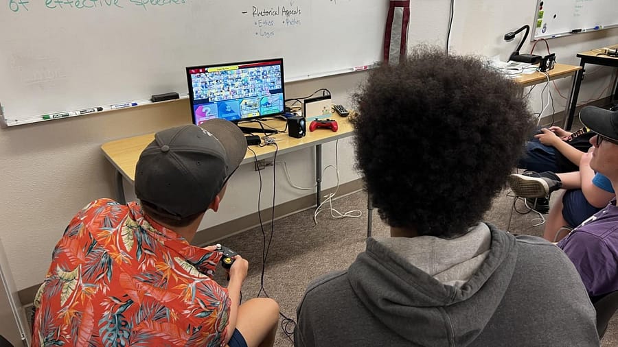two people sitting around a monitor playing super smash bros